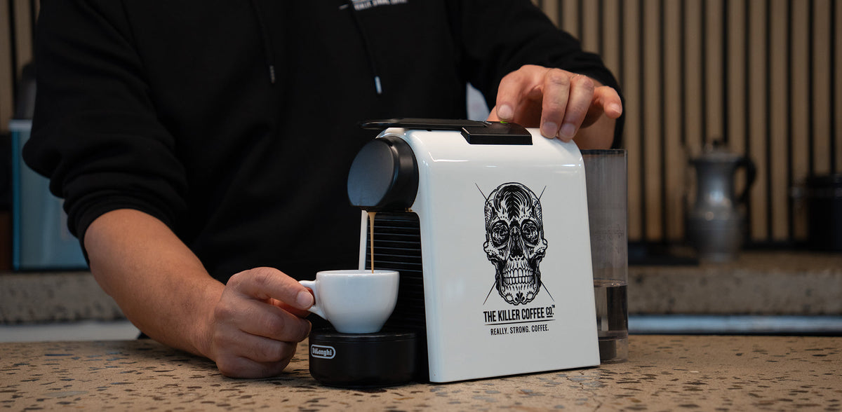 Killer Coffee capsule beside a Nespresso machine pouring espresso