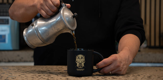 Moka pot on a stovetop with coffee in the top chamber