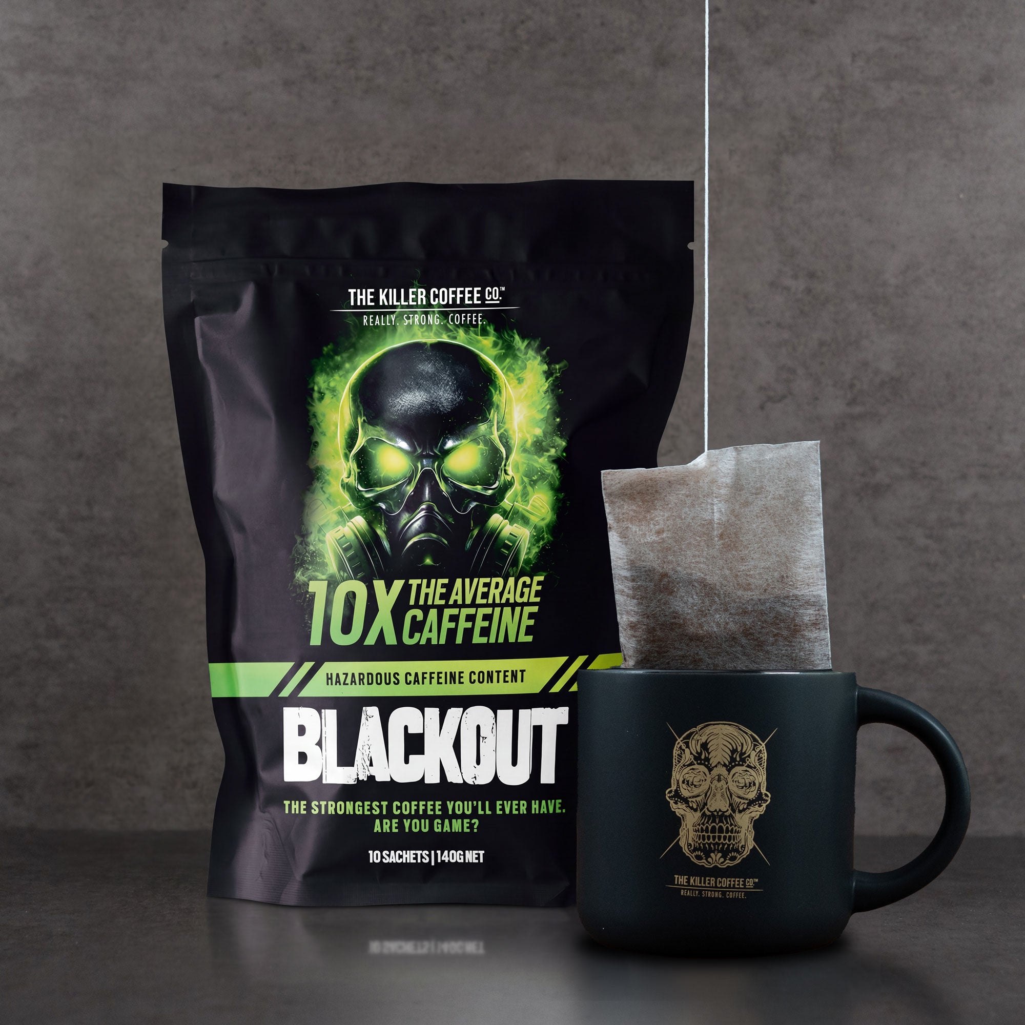 Killer Coffee Co. Blackout coffee package with a mug and tea bag on a gray background